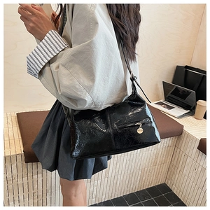 Detail of a vintage black glossy pleated shoulder bag with metallic charms and zipper pocket