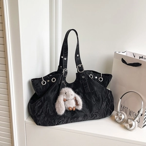 Large black pleated tote bag with silver eyelets and a plush rabbit charm decoration