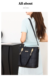 Detail view of the black tote bag featuring geometric stitching and gold chain accents