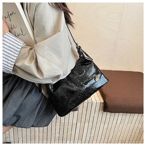 Close-up of shiny black wrinkled leather texture and golden round zipper on the bag