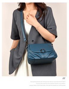Detail of navy blue grain leather crossbody bag with a round black metal ring buckle