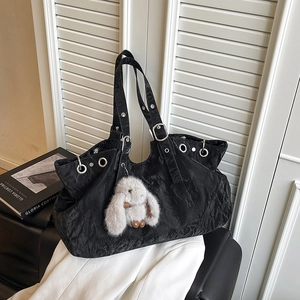 Black crinkled tote bag with silver eyelets and a white rabbit plush charm accessory