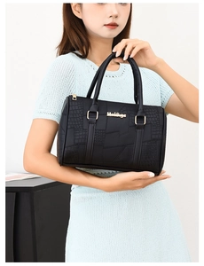 Detail of premium black faux crocodile leather handbag with elegant gold metal logo