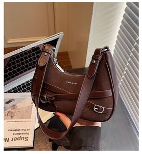 Détail du sac demi-lune en daim marron foncé avec boucle argentée et finitions cuir