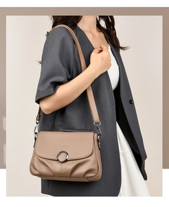 Detail of khaki leather shoulder bag with decorative metal ring and pleated flap design
