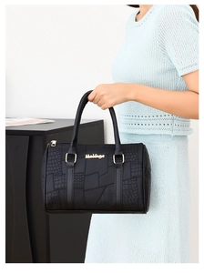 Close-up of black Boston bag showing crocodile texture stitching and gold metal logo