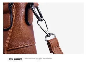 Detail of detachable shoulder strap with bronze metal hook on brown textured leather bag