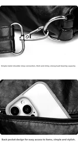 Detail of metal D-ring hardware and rear zipper pocket on black leather tote bag