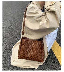 Close-up of brown woven leather shoulder bag with knotted strap details on a model