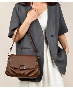 Close-up of brown lychee texture leather shoulder bag with circular metal buckle