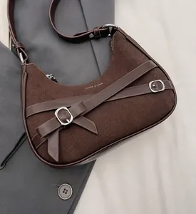 Détail du sac demi-lune marron en daim et cuir avec boucles argentées et nœud décoratif