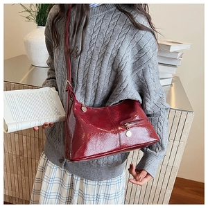 Detail of burgundy wrinkled leather shoulder bag with gold zipper and adjustable strap