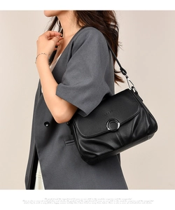 Close-up of black lychee grain leather handbag with silver round buckle and brand logo
