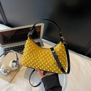 Yellow suede pearl shoulder bag with quilting and black strap in an office setting