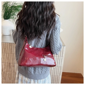 Detail of burgundy glossy patent leather bag with gold zipper and textured finish