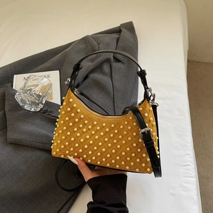 Quilted ginger yellow shoulder bag with white pearls and black straps in aesthetic setting
