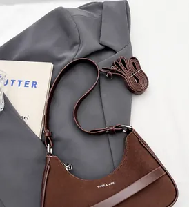 Détail du sac hobo en forme de croissant marron foncé avec bandoulière fine et logo