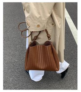 Detail of woven brown leather texture and decorative knot handle on the bucket bag