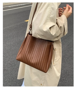 Close-up of dark brown woven shoulder bag with detailed cross-weave texture and silver hardware