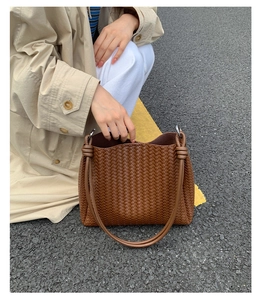 Detailed view of brown woven bucket bag featuring knotted handles and leather texture