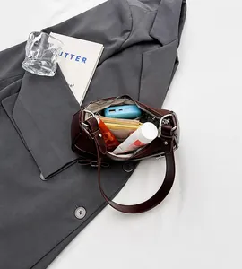 Détails de l'intérieur d'un petit sac demi-lune marron contenant batterie et portefeuille