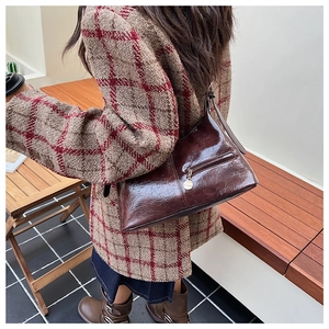Retro glossy wrinkled leather hobo bag in dark brown worn over the shoulder