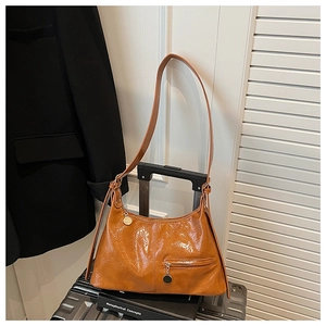 Detail of caramel oil wax leather handbag with glossy texture and metal zipper pocket