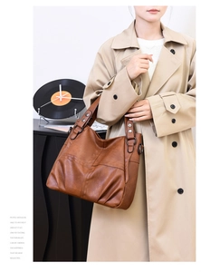 Close-up of brown PU leather tote bag with metal rivets and natural pleated texture