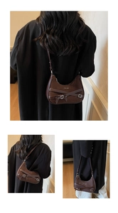 Vue macro du sac hobo marron foncé avec lanières en cuir et boucle argentée