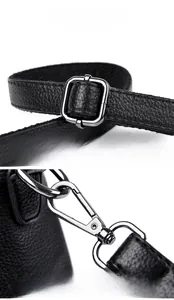 Detail of silver metal strap adjustment buckle and spring hook on black lychee leather bag