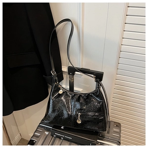 Detail of black glossy hobo bag with vintage texture and gold zipper on a suitcase