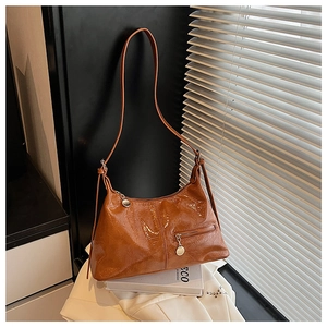 Close-up of brown glossy leather shoulder bag with zipper pocket and crinkled texture
