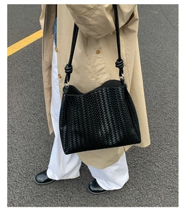 Close-up of minimalist black woven leather tote bag with fine lattice texture on a model