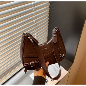 Détail du sac à bandoulière en cuir marron foncé avec boucle en métal et nœud