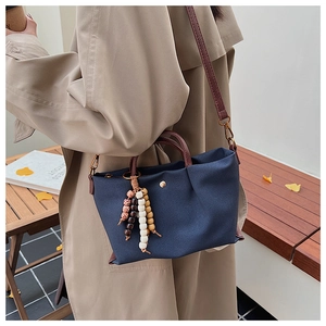 Detail of navy canvas tote with brown leather straps and colorful boho beaded charm