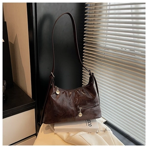 Detailed close-up of dark brown vintage shoulder bag with textured glossy leather and silver zipper
