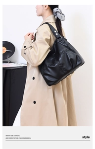 Detail of black pebbled leather hobo bag with silver ring hardware on a female model