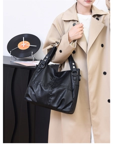 Close-up of black litchi pattern leather tote bag with silver rivets and metal ring detail