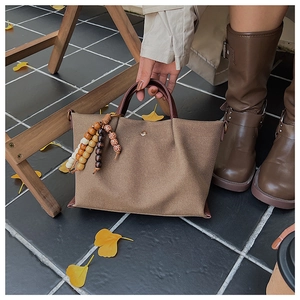 Close-up of brown canvas tote bag with ethnic style wooden beads and autumn leaves decor