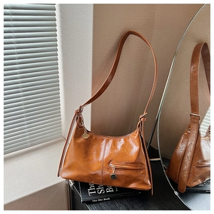 Close-up of caramel brown crescent bag with retro gold hardware and pleated texture