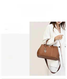Detail view of brown lychee grain leather tote bag with silver pendant and woven strap