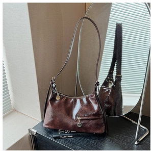 Close-up of vintage glossy leather shoulder bag with zipper pocket and metal pendant