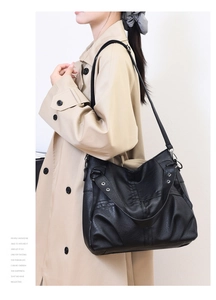 Detail view of the black soft leather shoulder bag with pebbled texture and rivets