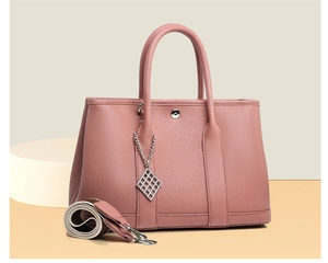 Detail of dusty pink lychee leather tote with silver snap button and chain charm