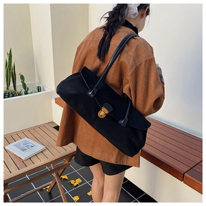 Close-up of vintage black faux suede Boston bag with gold buckle and long handles