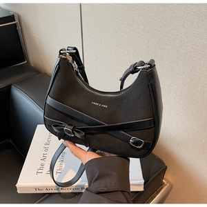 Détail du sac selle noir en daim avec lanières en cuir et boucle décorative noeud