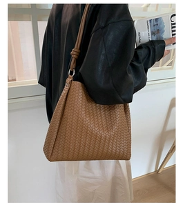 Detail of caramel woven leather tote bag with thick strap and metallic hardware