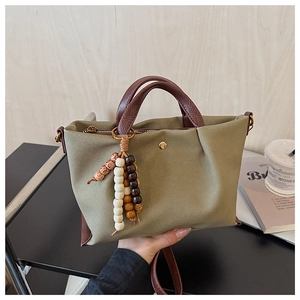 Close-up of olive green canvas tote bag with brown handles and colorful wooden beads