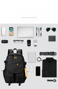 Flat lay of black laptop backpack with orange details and various organized travel items