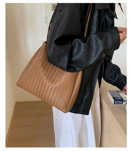 Detail of brown woven faux leather shoulder bag texture on model in leather jacket